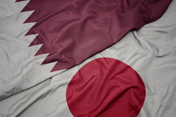 Falujące kolorowe flagi Japonii i flagi narodowej Kataru. — Zdjęcie stockowe