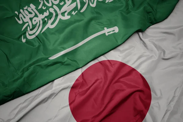 waving colorful flag of japan and national flag of saudi arabia.