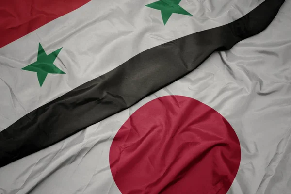 Sventolando bandiera colorata del Giappone e bandiera nazionale della Siria . — Foto Stock