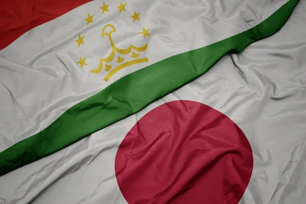 waving colorful flag of japan and national flag of tajikistan.