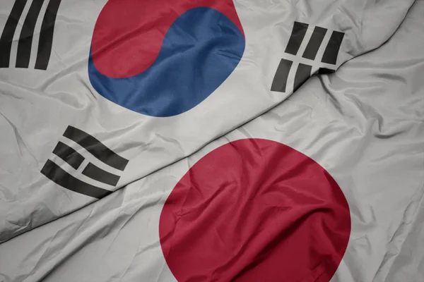 waving colorful flag of japan and national flag of south korea.