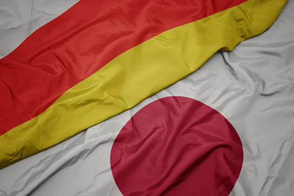 Acenando bandeira colorida do japão e bandeira nacional da ossétia do sul . — Fotografia de Stock