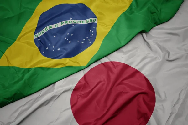 Ondeando colorida bandera de Japón y bandera nacional de Brasil . — Foto de Stock