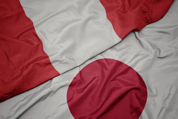 Zwaaiende kleurrijke vlag van Japan en de nationale vlag van Peru. — Stockfoto