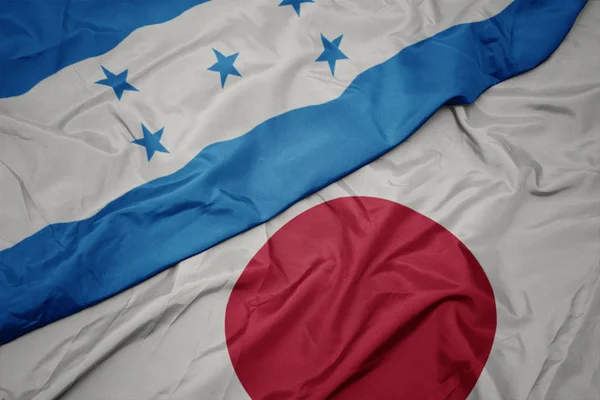 Agitant drapeau coloré du Japon et drapeau national des honduras . — Photo