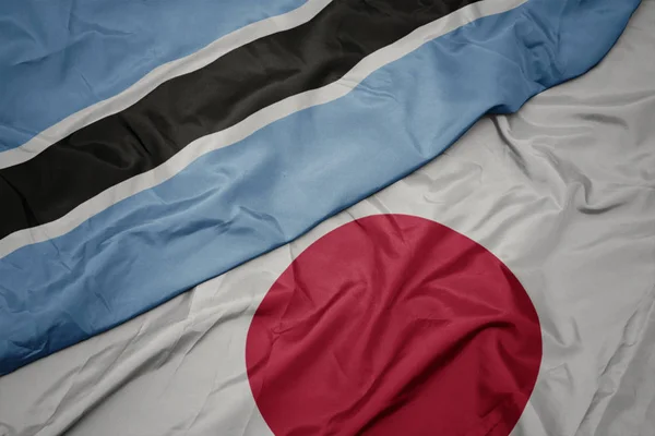 Agitant drapeau coloré du Japon et drapeau national du Botswana . — Photo