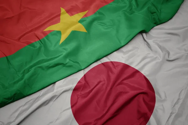 Ondeando colorida bandera de Japón y bandera nacional de Burkina faso . — Foto de Stock