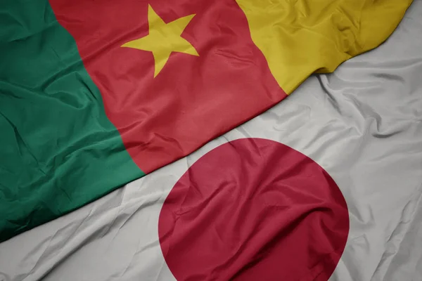 waving colorful flag of japan and national flag of cameroon.