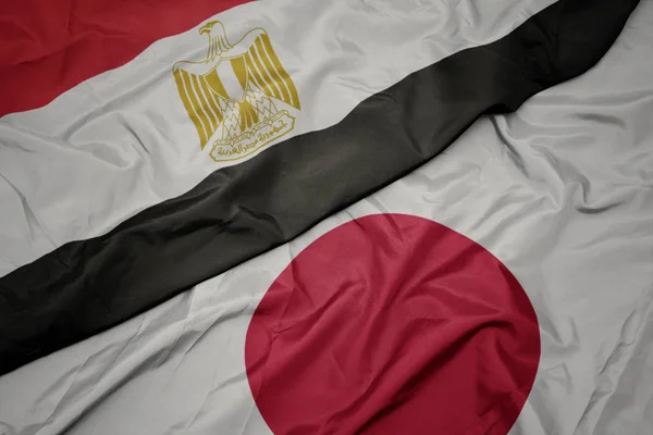 waving colorful flag of japan and national flag of egypt.
