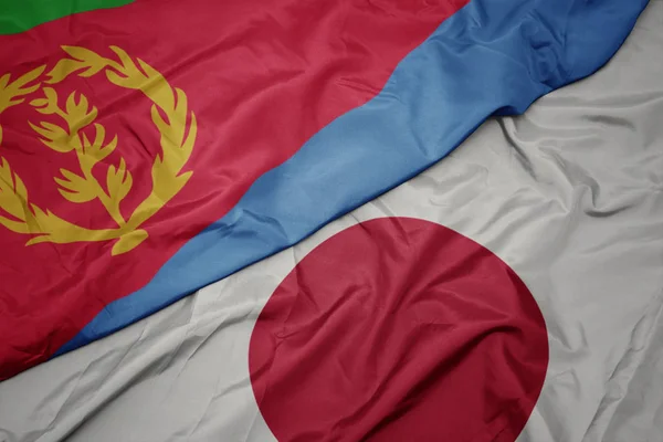waving colorful flag of japan and national flag of eritrea.