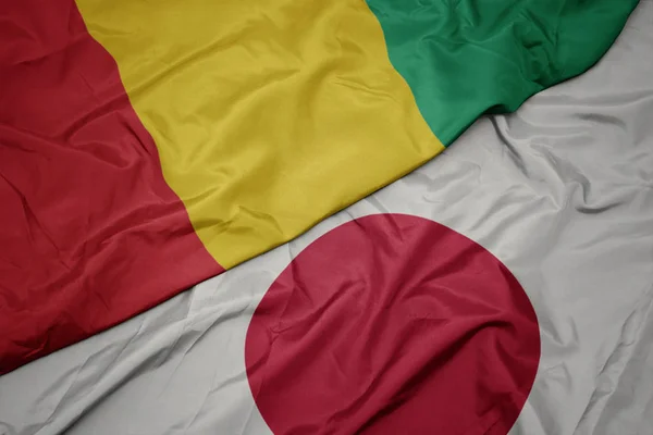Vifta färgglada flagga av Japan och nationella flaggan i Guinea. — Stockfoto