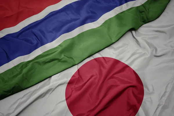 Acenando bandeira colorida do japão e bandeira nacional da gâmbia . — Fotografia de Stock