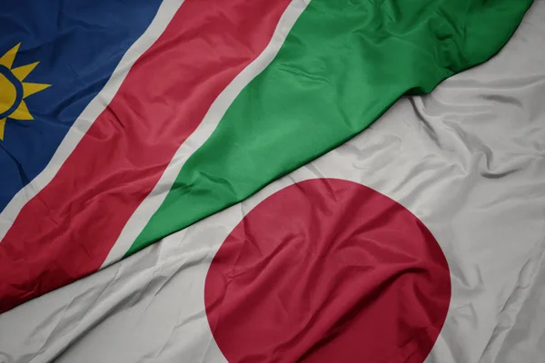 waving colorful flag of japan and national flag of namibia.