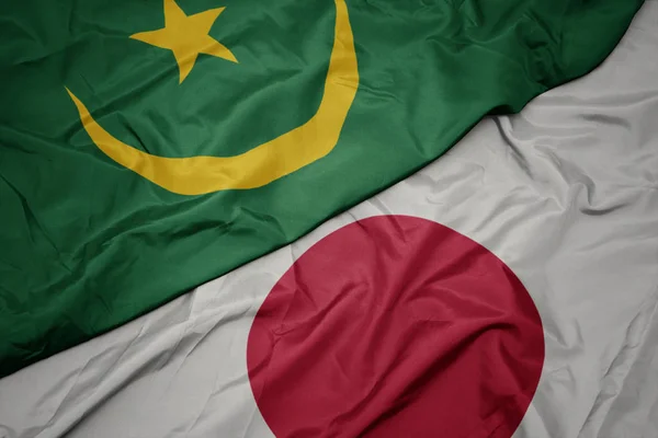 waving colorful flag of japan and national flag of mauritania.