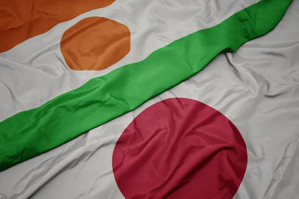 waving colorful flag of japan and national flag of niger.