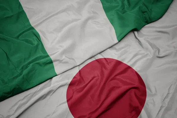 waving colorful flag of japan and national flag of nigeria.