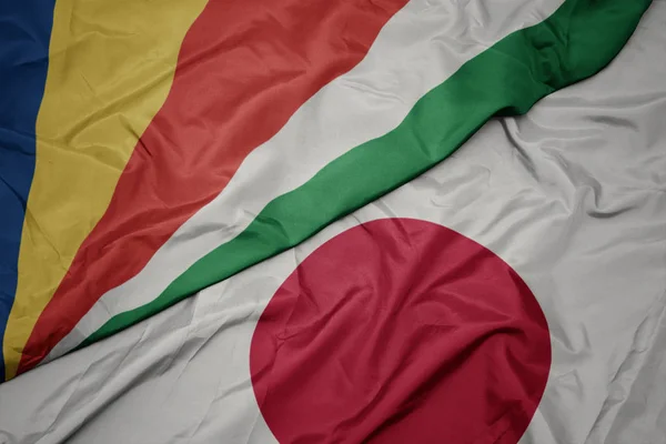 Mávající barevná vlajka Japonska a národní vlajky Seychel. — Stock fotografie