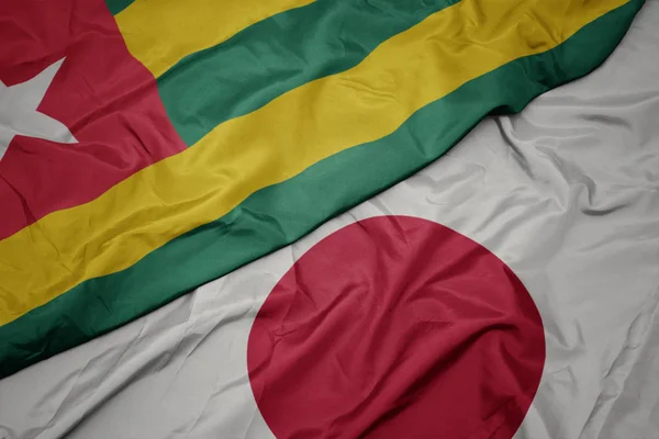 waving colorful flag of japan and national flag of togo.