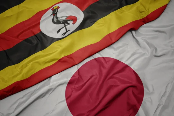 Размахивая красочным флагом Японии и национальным флагом Уганды . — стоковое фото