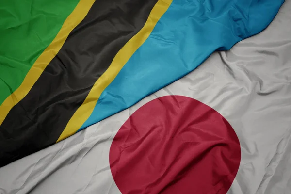 waving colorful flag of japan and national flag of tanzania.