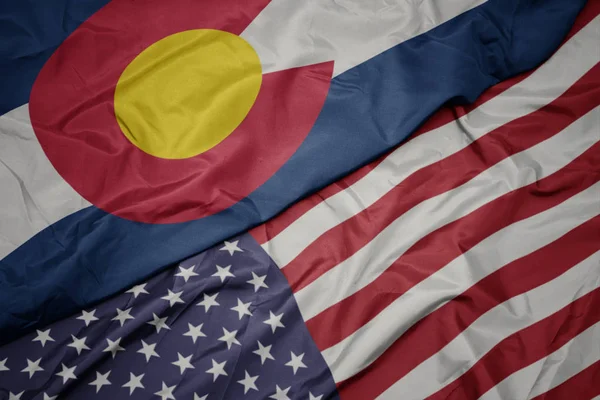 Agitant le drapeau coloré des États-Unis d'Amérique et le drapeau de l'État colorado . — Photo