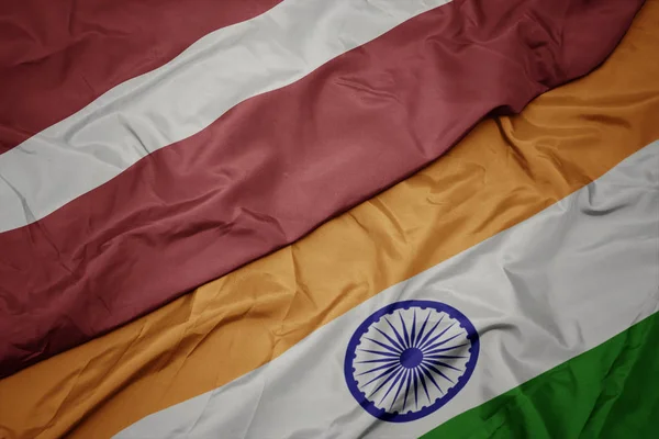 Agitant drapeau coloré de l'Inde et drapeau national de latvia . — Photo