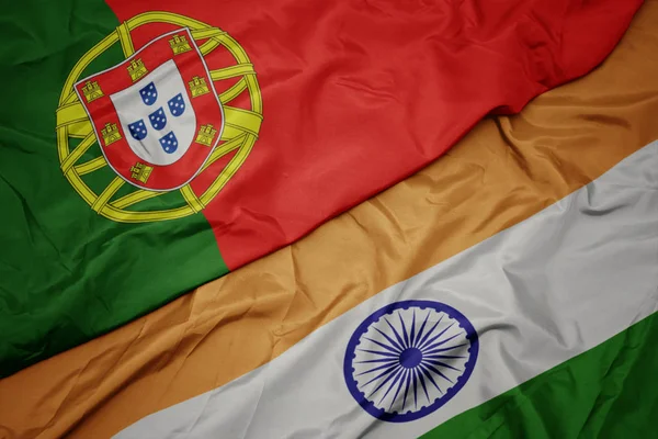 waving colorful flag of india and national flag of portugal.