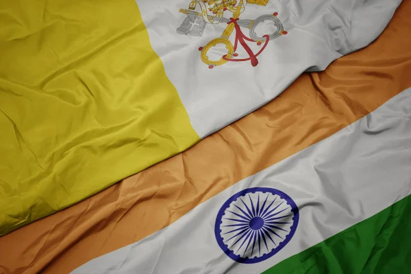 waving colorful flag of india and national flag of vatican city.