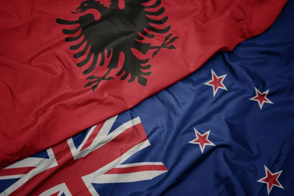 Yeni zelanda ve arnavutluk ulusal bayrağı renkli bayrak sallayarak. — Stok fotoğraf