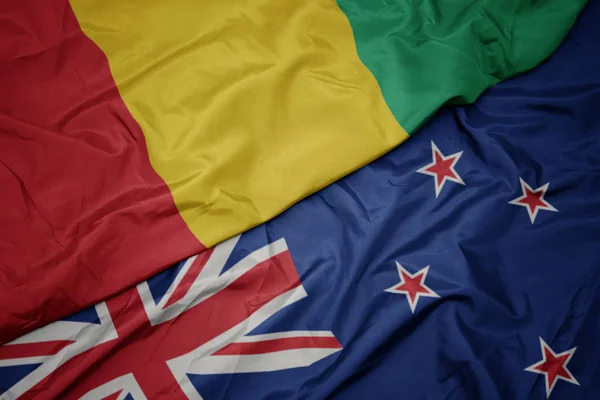 Waving colorful flag of new zealand and national flag of guinea. — Stock Photo, Image