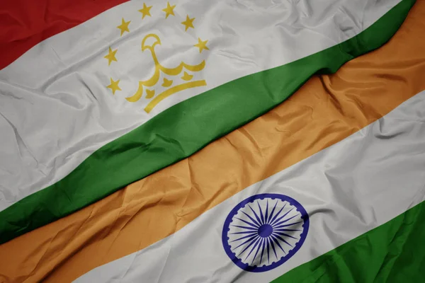 waving colorful flag of india and national flag of tajikistan.