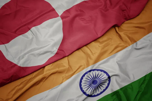 waving colorful flag of india and national flag of greenland.