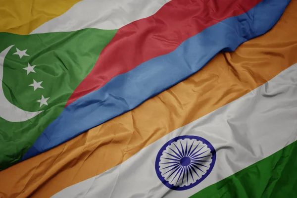 waving colorful flag of india and national flag of comoros.