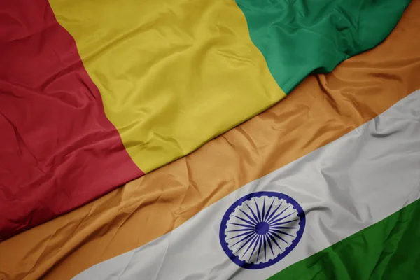 waving colorful flag of india and national flag of guinea.