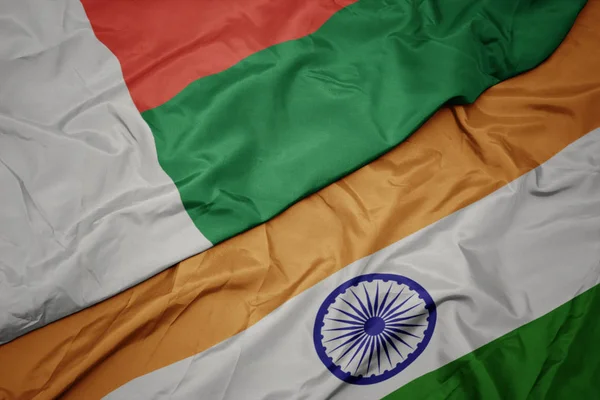 waving colorful flag of india and national flag of madagascar.