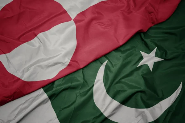 Zwaaiende kleurrijke vlag van Pakistan en de nationale vlag van Groenland. — Stockfoto