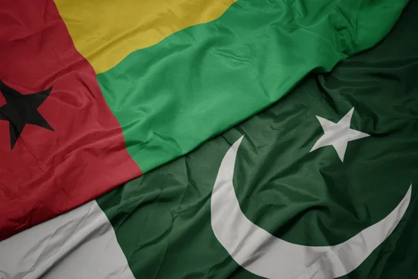 Ondeando colorida bandera de Pakistán y bandera nacional de Guinea Bissau . — Foto de Stock