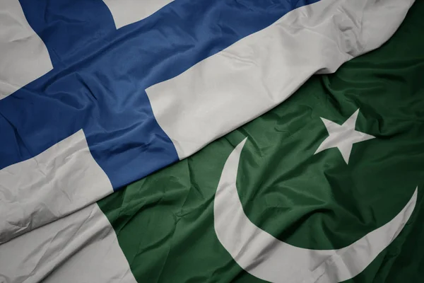 Agitant le drapeau coloré du pakistan et le drapeau national de la Finlande . — Photo