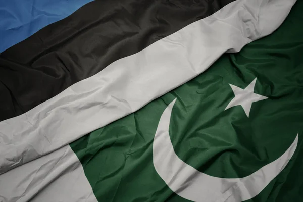 Zwaaiende kleurrijke vlag van Pakistan en de nationale vlag van Estland. — Stockfoto