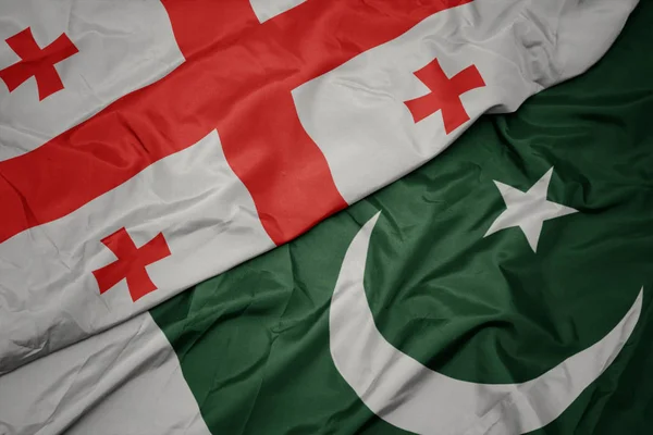 Agitant le drapeau coloré du pakistan et le drapeau national de la géorgie . — Photo