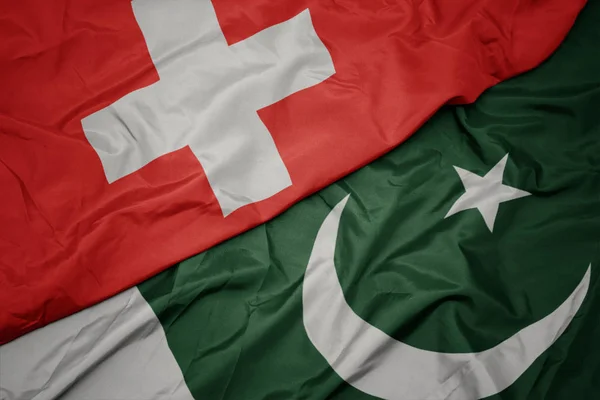 Agitant drapeau coloré du pakistan et drapeau national de la Suisse . — Photo