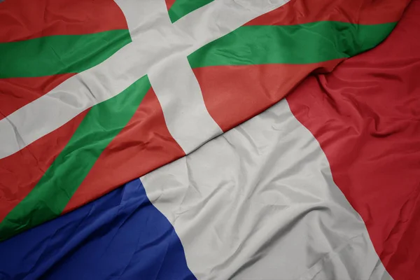 Agitant le drapeau coloré de la France et le drapeau national du Pays basque . — Photo