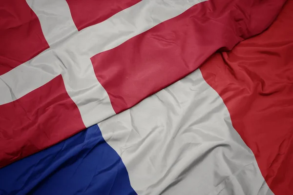 Zwaaiende kleurrijke vlag van Frankrijk en de nationale vlag van Denemarken. — Stockfoto