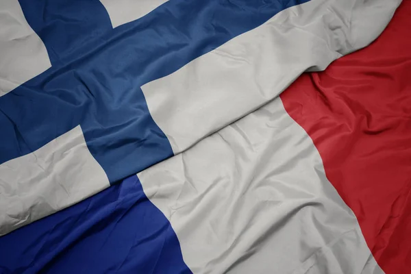 Размахивая красочным флагом Франции и государственным флагом Финляндии . — стоковое фото
