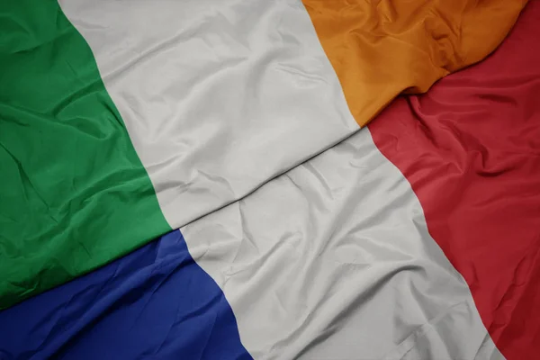 waving colorful flag of france and national flag of ireland.