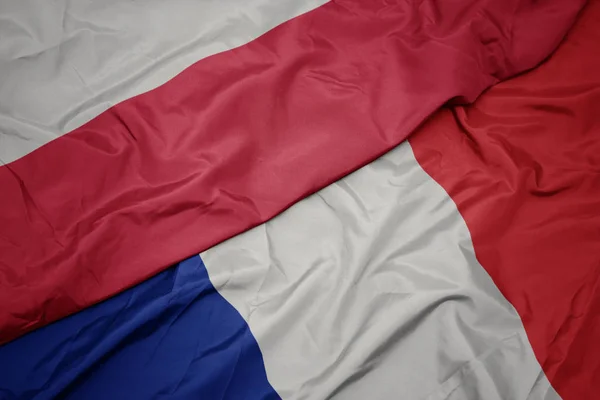 Mávající barevná vlajka Francie a národní vlajka Polska. — Stock fotografie