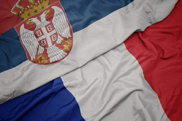 Розмахуючи барвистий прапор Франції та державного прапора Сербії. — стокове фото