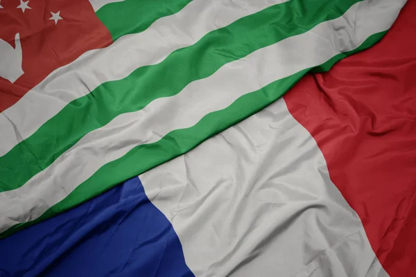 Ondeando colorida bandera de Francia y bandera nacional de abjasia . — Foto de Stock