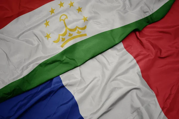 Sventolando bandiera colorata della Francia e bandiera nazionale del tajikistan . — Foto Stock