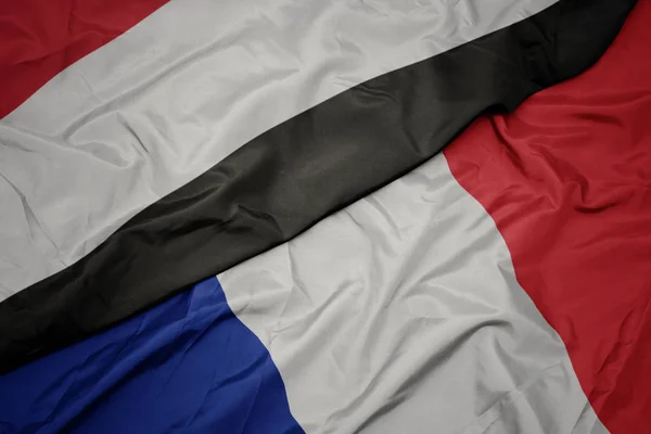 Schwenken bunte Fahne von Frankreich und Nationalflagge von Jemen. — Stockfoto